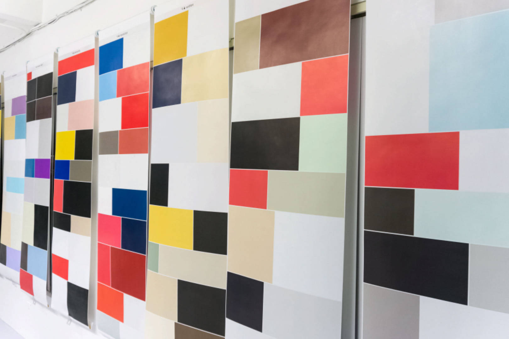 Window blinds on a wall that show a pattern of rectangles and cubes with different colors 